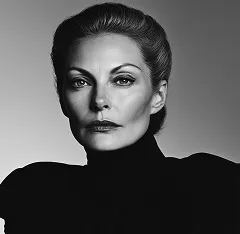 Black-and-white portrait of a woman with styled hair wearing a high-necked top looking directly at the camera.